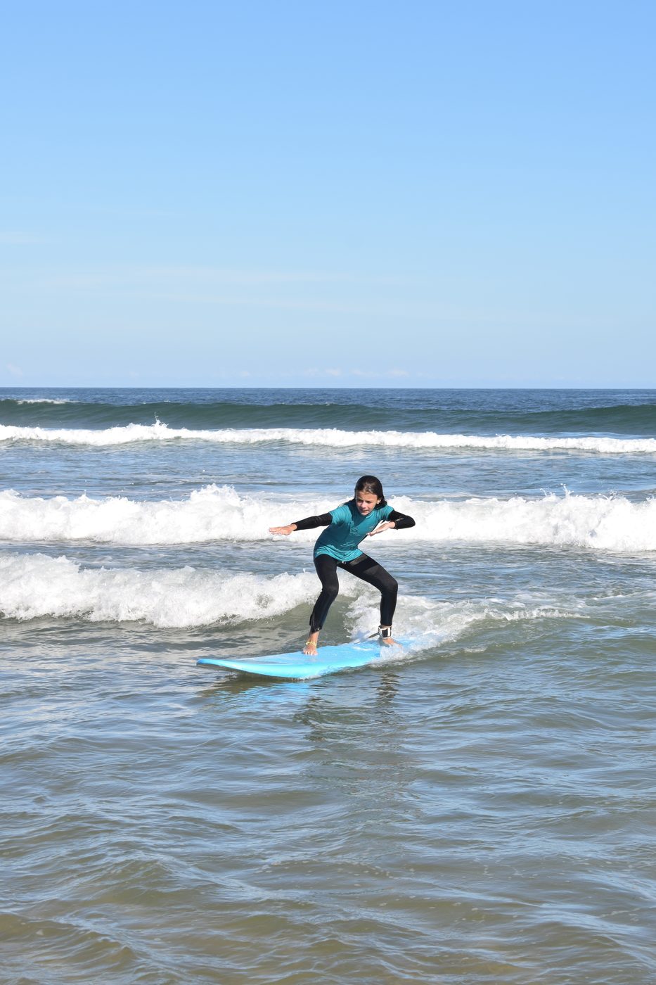 Alumna parándose en la tabla durante una clase de surf en Punta del Este